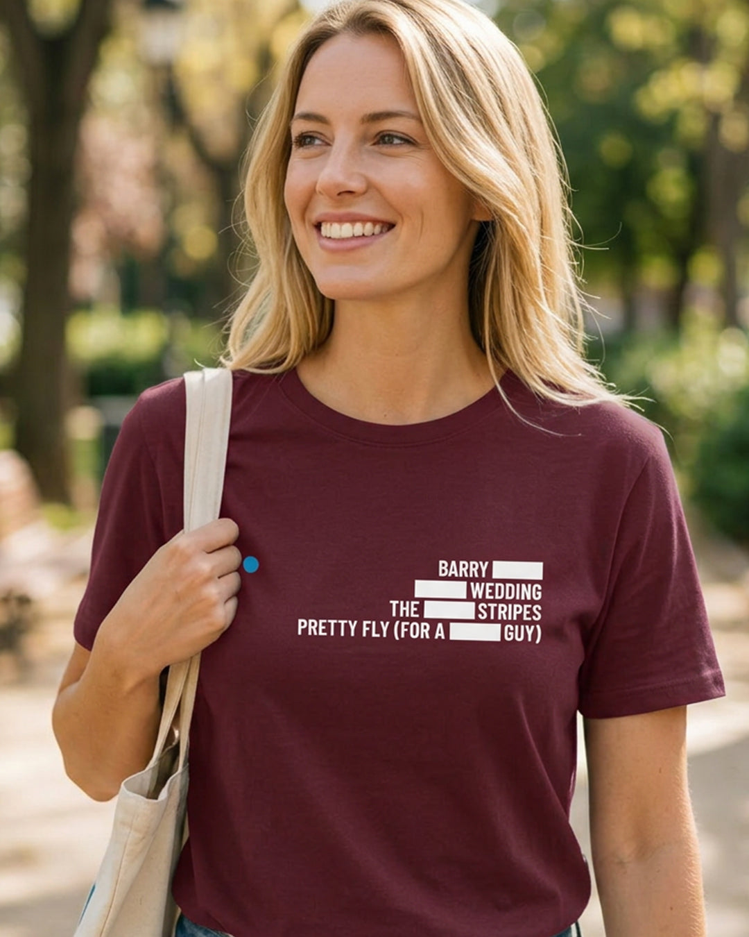 Woman wearing a maroon t-shirt with text, standing outdoors.