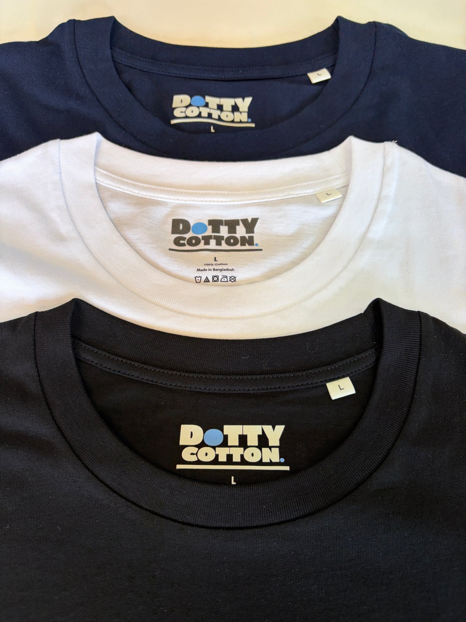 Three folded t-shirts in navy, white, and black with 'Dotty Cotton' branding.
